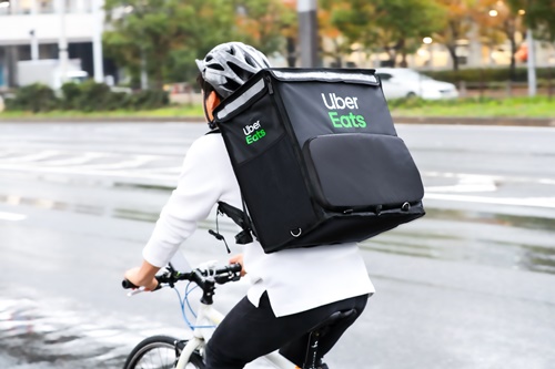 Uber Eatsのバッグを持って自転車で配達している人